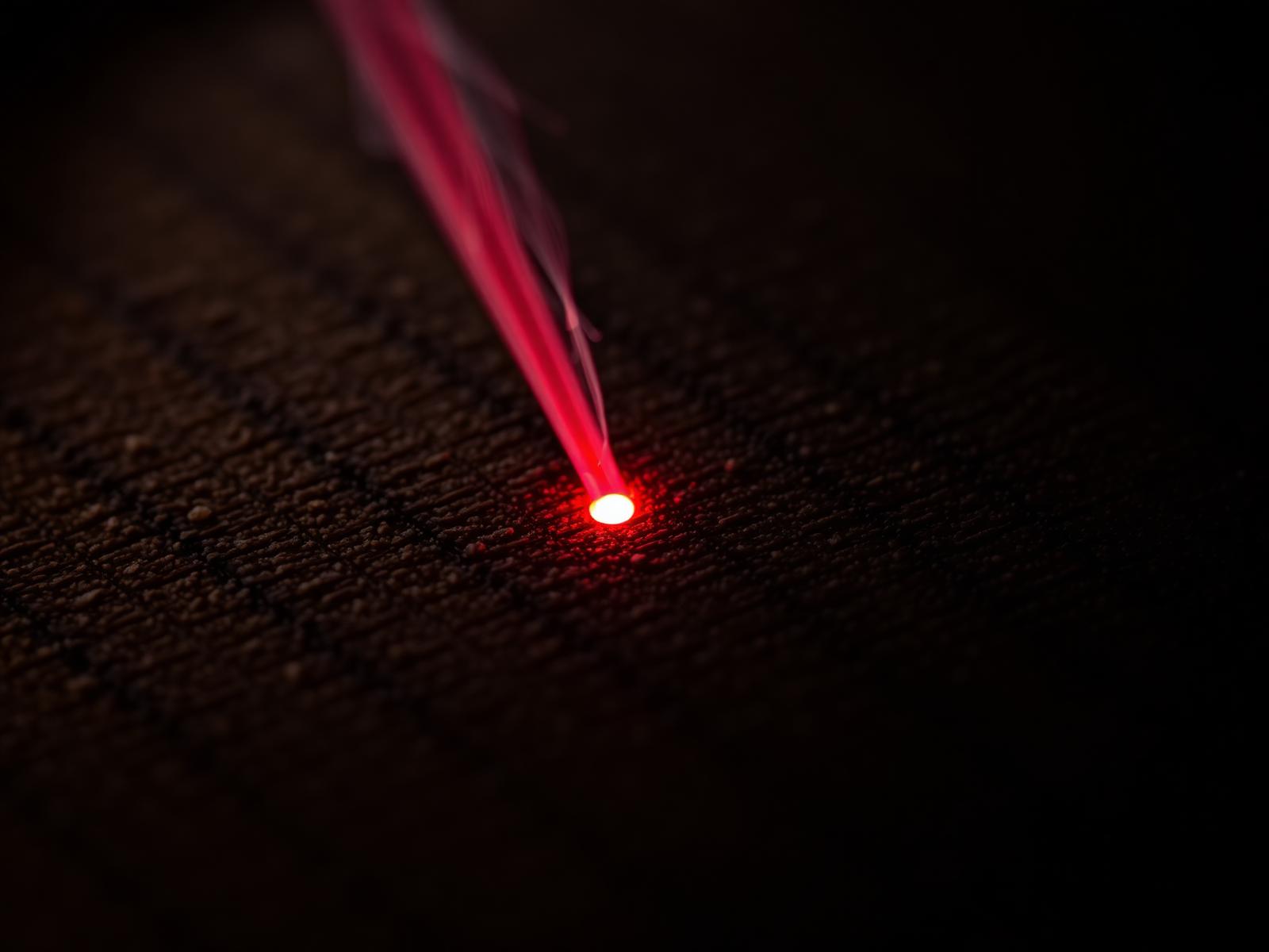 Precision laser engraving a fine detail into dark walnut wood